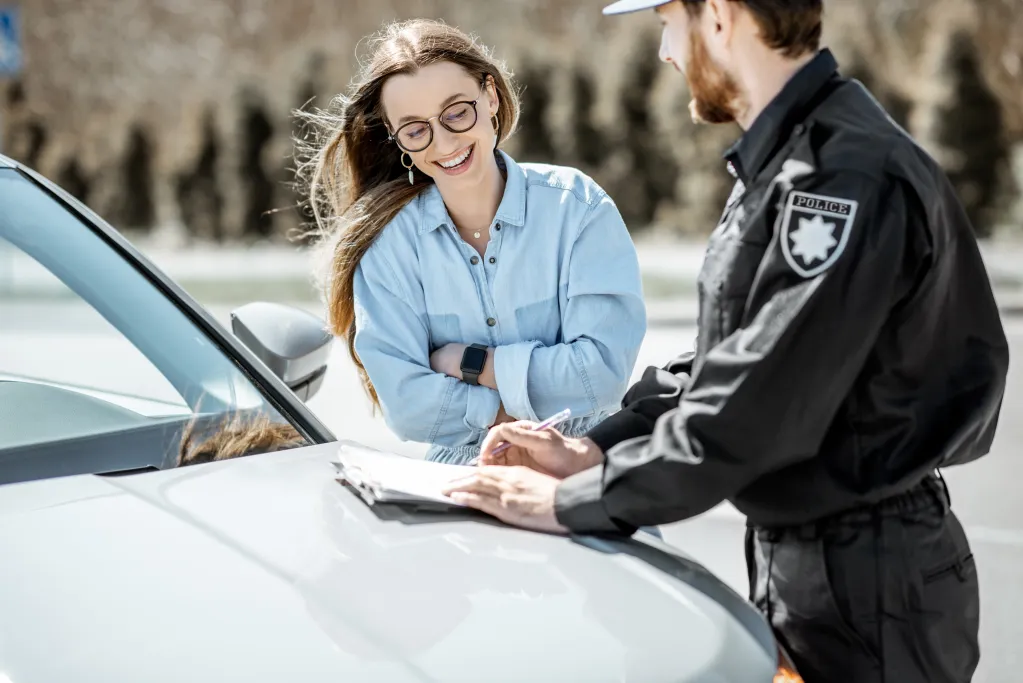 Mujer hablando con un oficial de policía con coche.
